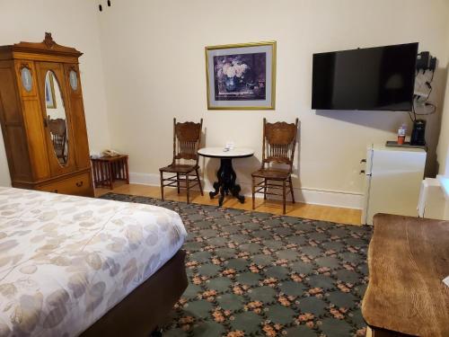 a bedroom with a bed and a table and a tv at Manresa Castle in Port Townsend