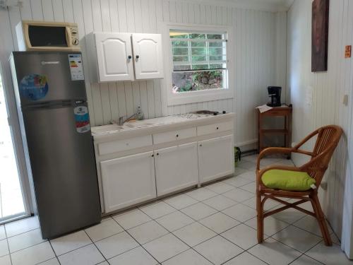 a kitchen with a refrigerator and a chair in it at Appart'hotel La croisière in Gourbeyre