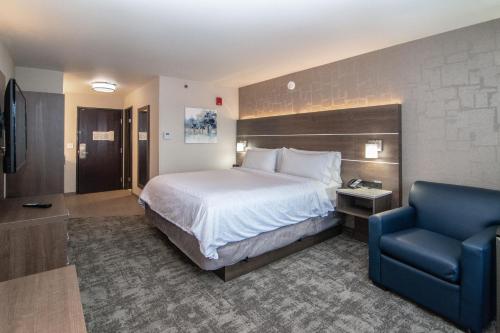 um quarto de hotel com uma cama e uma cadeira azul em Holiday Inn Express Spokane-Downtown, an IHG Hotel em Spokane