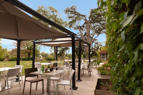 a patio with tables and chairs and umbrellas at The Originals Boutique, Parc Hôtel, Orléans Sud in La Chapelle-Saint-Mesmin