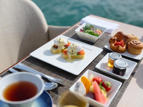 a table with two plates of food and a cup of tea at ANA InterContinental Manza Beach Resort by IHG in Onna