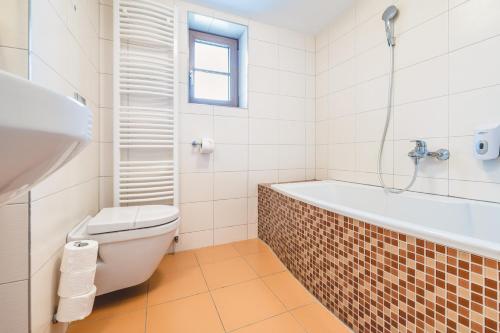 a bathroom with a tub and a toilet and a sink at Hotel Resort Relax in Dolní Vltavice