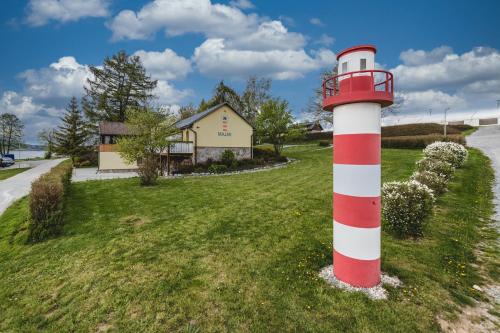 a red and white lighthouse in the grass near a house at Hotel Resort Relax in Dolní Vltavice