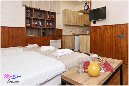 a bedroom with two beds and a table with a pitcher of orange juice at Masur House and Tours in Yerevan