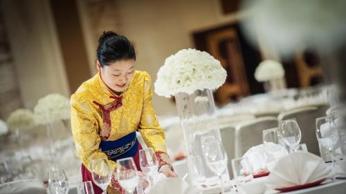 a woman standing in front of a table with wine glasses at InterContinental Lhasa Paradise by IHG in Lhasa