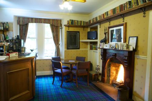 a living room with a table and a fireplace at Loch Kinord Hotel in Dinnet