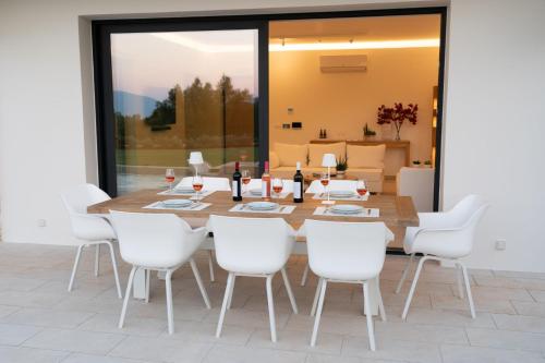 a dining room with a wooden table and white chairs at Ionian Trilogy Luxury Villas in Sami