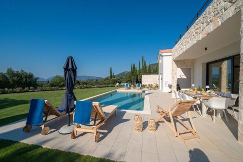 a patio with chairs and an umbrella and a pool at Ionian Trilogy Luxury Villas in Sami