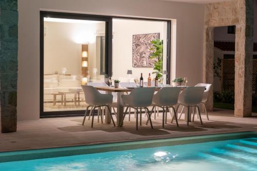 un comedor con mesa y sillas junto a una piscina en Ionian Trilogy Luxury Villas, en Sami