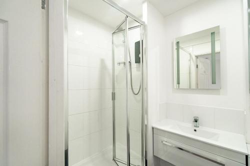 a white bathroom with a shower and a sink at H.V Apartments in Sheffield
