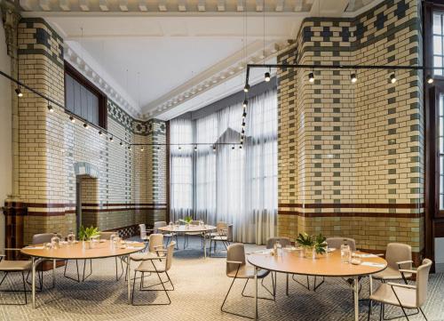 a restaurant with tables and chairs and large windows at Kimpton Clocktower by IHG in Manchester
