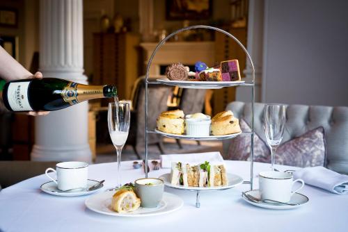 a person pouring a bottle of wine on a table with food at The Milner York in York