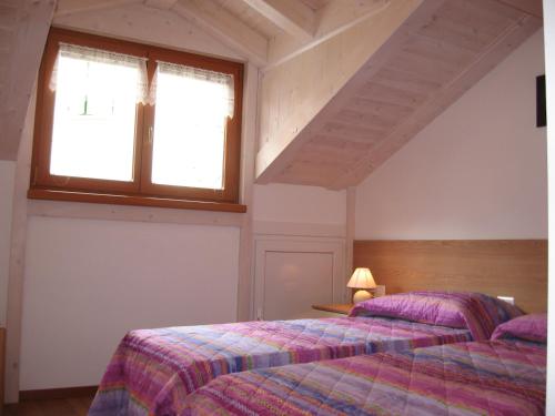 a bedroom with two beds and a window at Casa Rondine in Molveno