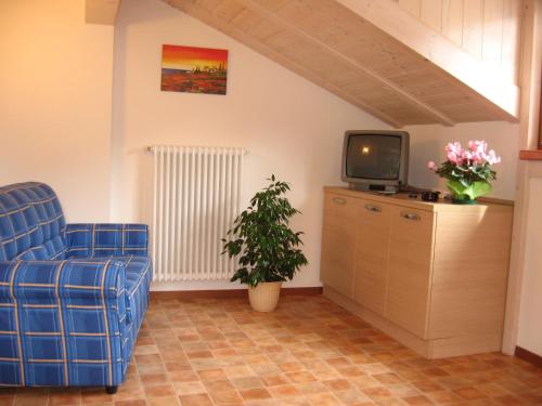 a living room with a blue chair and a tv at Casa Rondine in Molveno
