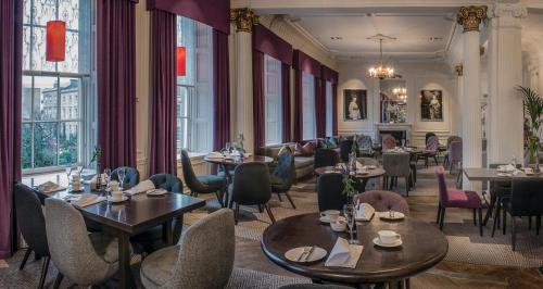 a restaurant with tables and chairs and windows at Kimpton Blythswood Square Hotel & Spa by IHG in Glasgow