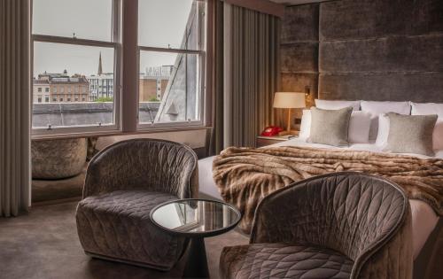 a hotel room with a bed and two chairs and a window at Kimpton Blythswood Square Hotel & Spa by IHG in Glasgow