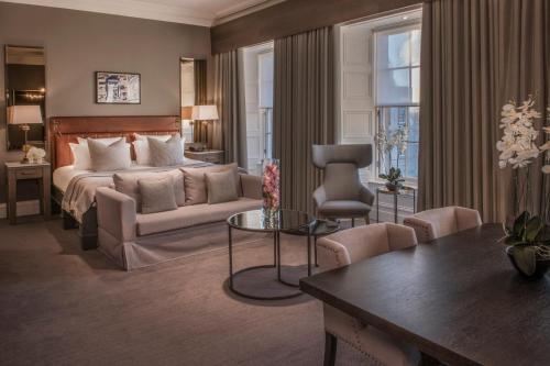 a bedroom with a bed and a couch and a table at Kimpton Blythswood Square Hotel & Spa by IHG in Glasgow