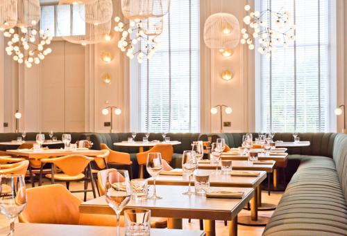 a restaurant with tables and chairs and chandeliers at Kimpton Blythswood Square Hotel & Spa by IHG in Glasgow