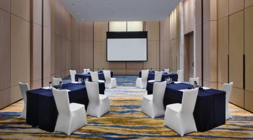 a conference room with tables and white chairs and a screen at InterContinental Chongqing Raffles City by IHG in Chongqing