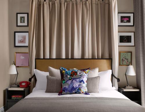 a bedroom with a bed with a headboard and pillows at Kimpton Fitzroy London by IHG in London