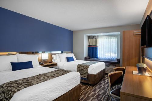 a hotel room with two beds and a desk at Microtel Inn & Suites by Wyndham Burlington in Burlington