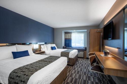 a hotel room with two beds and a flat screen tv at Microtel Inn & Suites by Wyndham Burlington in Burlington
