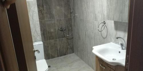 La salle de bains est pourvue d'une douche, d'un lavabo et de toilettes. dans l'établissement Olive Tree Apart Hotel, à Muğla