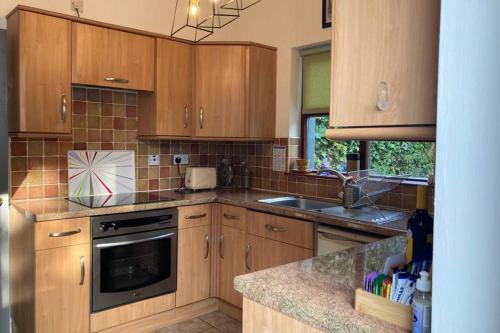 a kitchen with wooden cabinets and a sink at Temple-Effin Self Catering Holiday Cottage in Whitehead