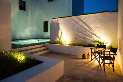 a patio with chairs and a swimming pool at night at Aljana Guest House Beja in Beja