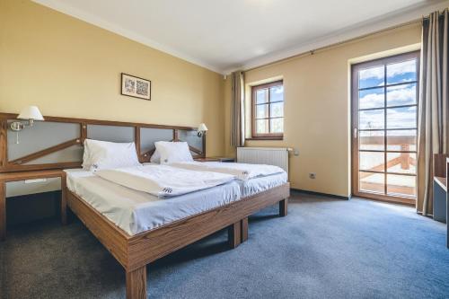 Hotel Resort Relax في Dolní Vltavice: غرفة نوم بسرير كبير مع شراشف بيضاء