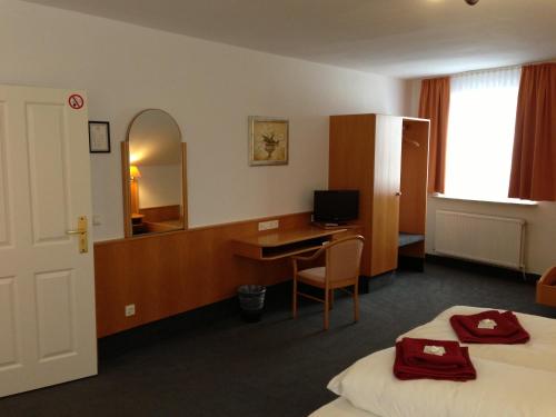 a hotel room with a desk and a mirror at Hotel & Restaurant Jägerstuben in Ritterhude