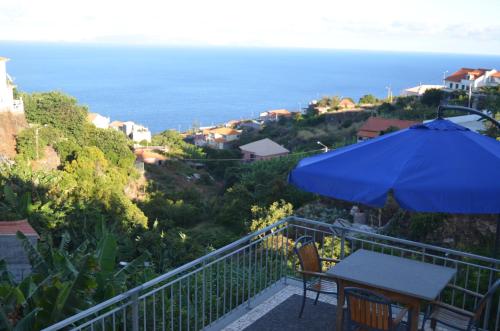 a patio with a table and an umbrella and the ocean at Descobrir Madeira in Gaula