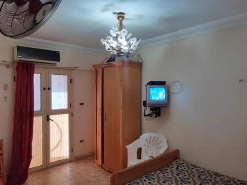 a living room with a television and a chandelier at شاليه عايدة بيتش للعائلات فقط in El Alamein