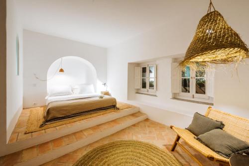 een slaapkamer met een bed en een stoel bij Aljana Guest House Beja in Beja