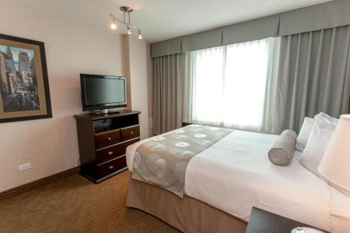 a hotel room with a bed and a television at Campus Tower Suite Hotel in Edmonton