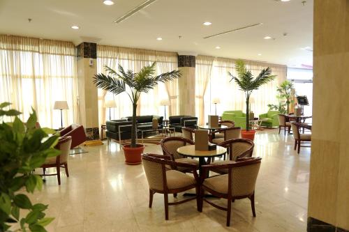 eine Hotellobby mit Tischen, Stühlen und Pflanzen in der Unterkunft Alazhar Palace Hotel in Al Qunfudhah