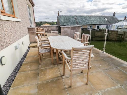 a patio with a wooden table and chairs at Tarnacrye in Annan