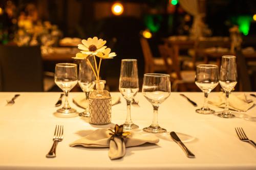 a table with wine glasses and a vase of flowers at Pousada Recanto do Arraial in Arraial d'Ajuda