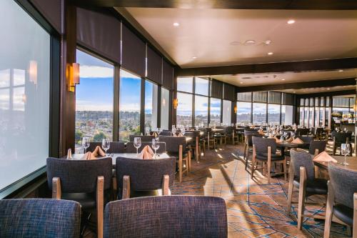a dining room with tables and chairs and windows at Holiday Inn Long Beach - Airport by IHG in Long Beach