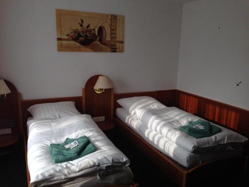 two twin beds in a room with a picture on the wall at Hotel & Restaurant Jägerstuben in Ritterhude