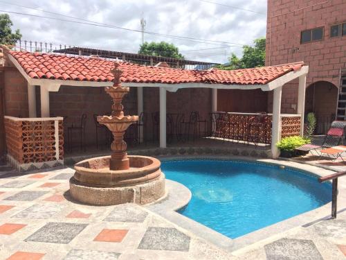 a swimming pool with a fountain in a yard at OYO Hotel Brisas Del Pacífico in Puerto Vallarta
