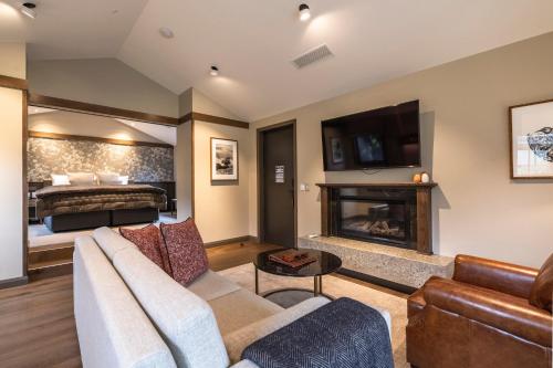 a living room with a couch and a fireplace and a bed at Gibbston Valley Lodge and Spa in Queenstown
