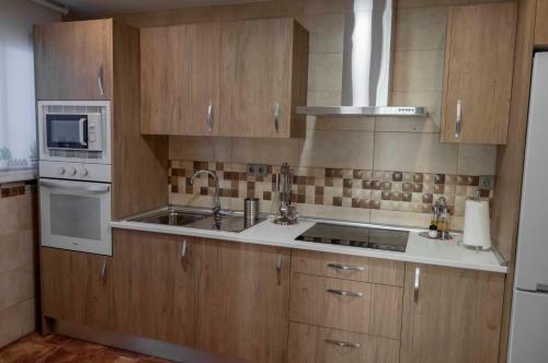 a kitchen with wooden cabinets and a sink and a microwave at Calma cañada in Talavera de la Reina