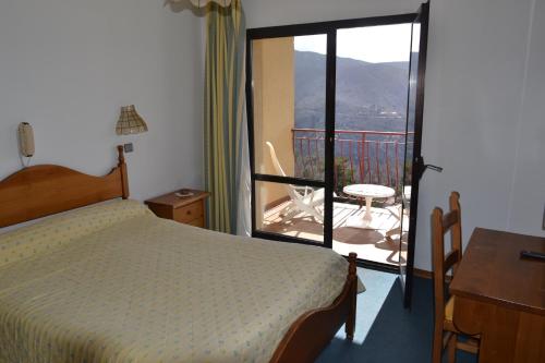 1 dormitorio con cama y vistas a un balcón en Hôtel Aïtone, en Evisa