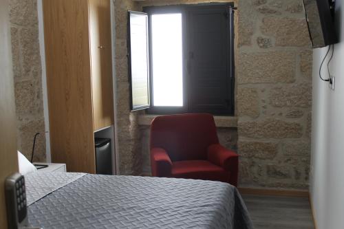 a bedroom with a bed and a chair and a window at ALOJAMENTO GIRASSOL - Guest House - Quarto com casa de banho privativa in Castelo Branco