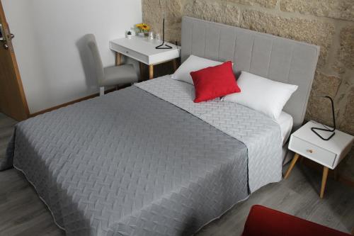 a bedroom with a bed with a red pillow on it at ALOJAMENTO GIRASSOL - Guest House - Quarto com casa de banho privativa in Castelo Branco