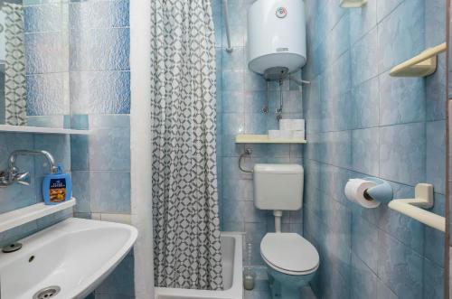 a blue tiled bathroom with a toilet and a sink at Apartments Green Street in Batalaži