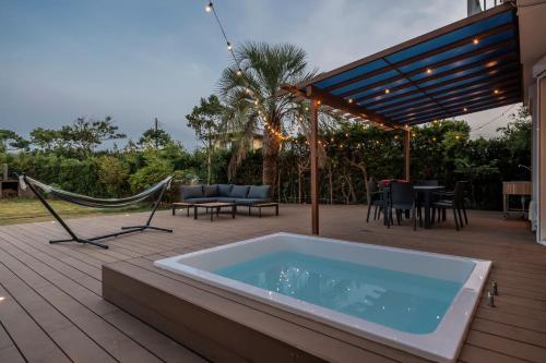 einen Whirlpool auf einer Terrasse mit einer Hängematte in der Unterkunft private villa 九十九里 in Kujukuri