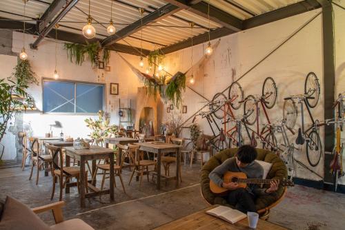 a man sitting in a chair playing a guitar in a restaurant at Exclusive Accommodation 9bicycle 9ppl in Tokyo