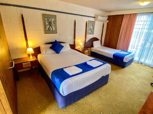 a hotel room with two beds with blue sheets at Snow Season Motor Inn in Cooma